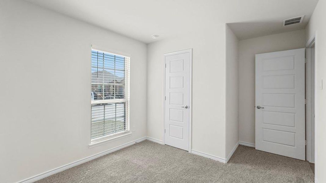 This room features light-colored walls, carpeted flooring, and a window with blinds