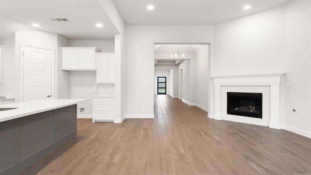 Unfurnished living room with a notable chandelier, sink, and light hardwood / wood-style flooring