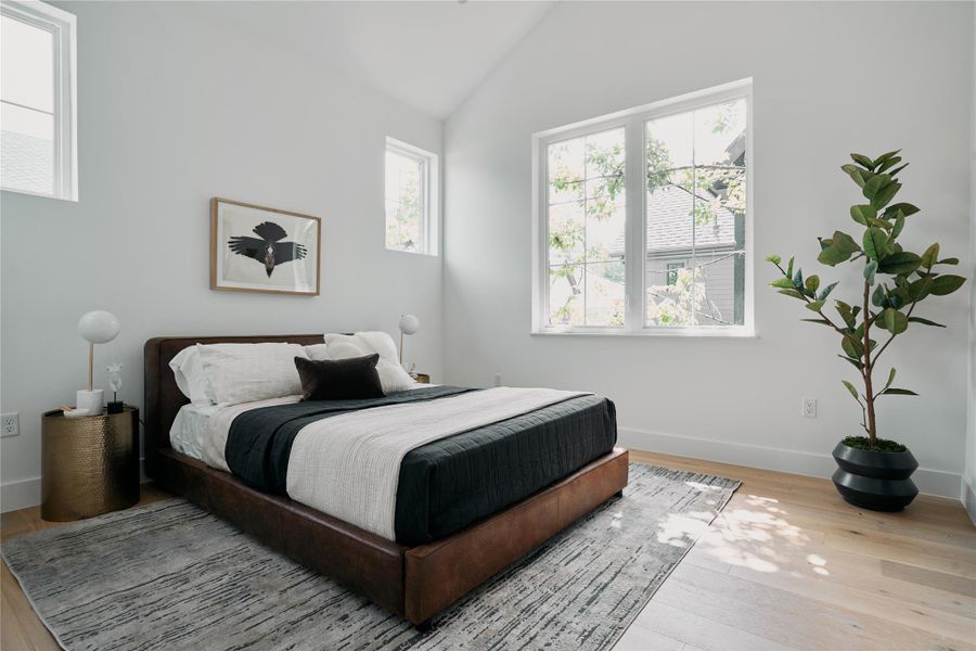 Bedroom featuring vaulted ceiling, wood finished floors, and baseboards Bedroom featuring vaulted ceiling, wood finished floors, and baseboards