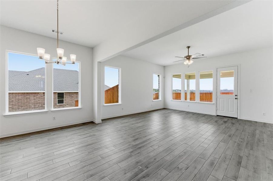 Unfurnished dining area with ceiling fan, a chandelier, and light wood-style floors