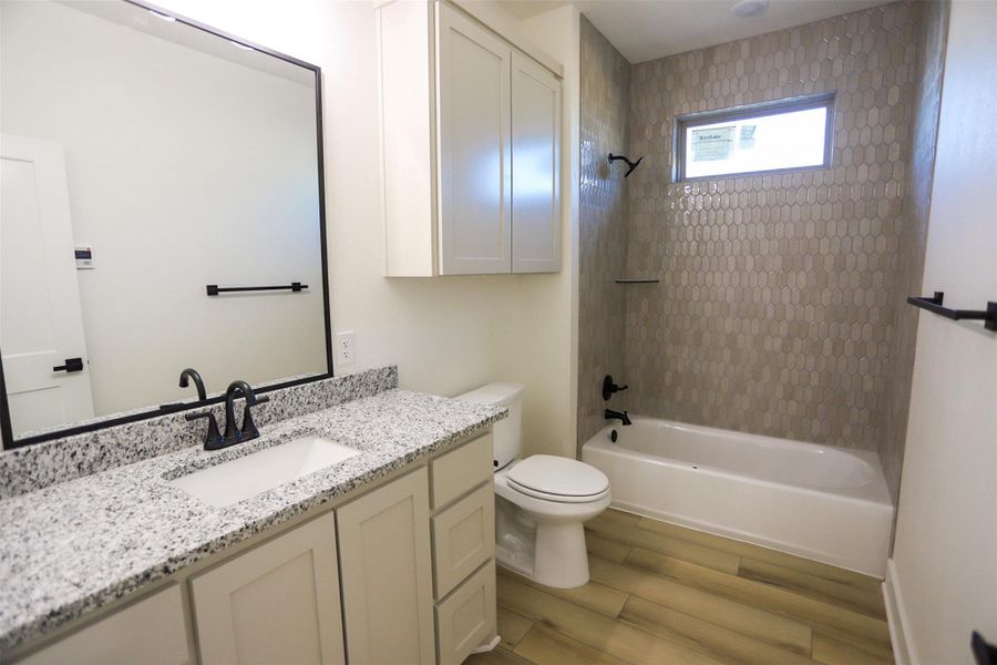 Full bath with vanity, washtub / shower combination, and light wood-style floors