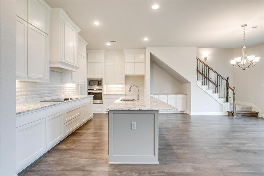 Kitchen featuring sink, wood-type flooring, tasteful backsplash, and stainless steel appliances