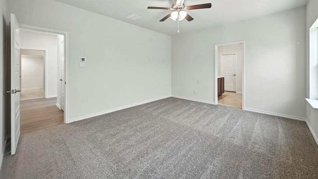 Unfurnished bedroom with light colored carpet, a ceiling fan, and ensuite bath