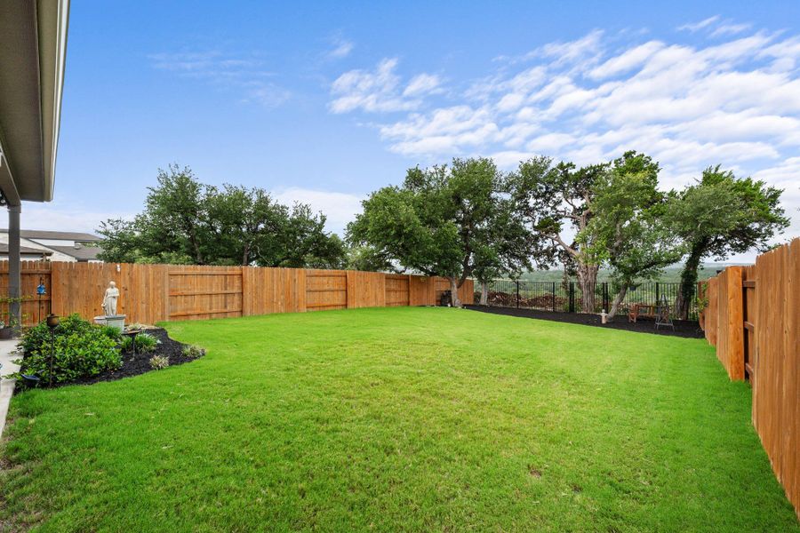 A spacious backyard with mature trees and a sturdy wooden fence, offering ample space for outdoor activities. A spacious backyard with mature trees and a sturdy wooden fence, offering ample space for outdoor activities.