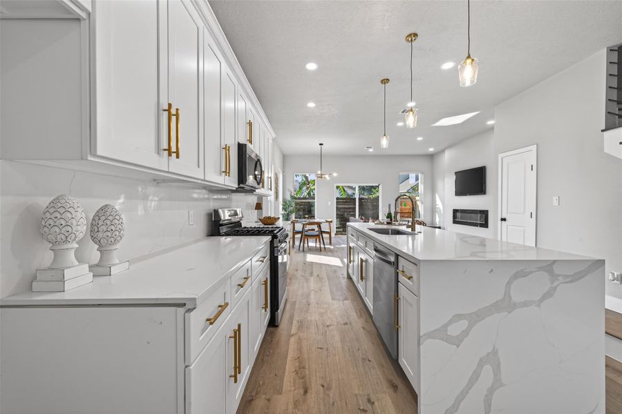 Designer kitchen anchored by an oversized quartz waterfall island with dramatic veining, offering generous prep space, seating, and seamless entertaining flow into the living and dining areas.