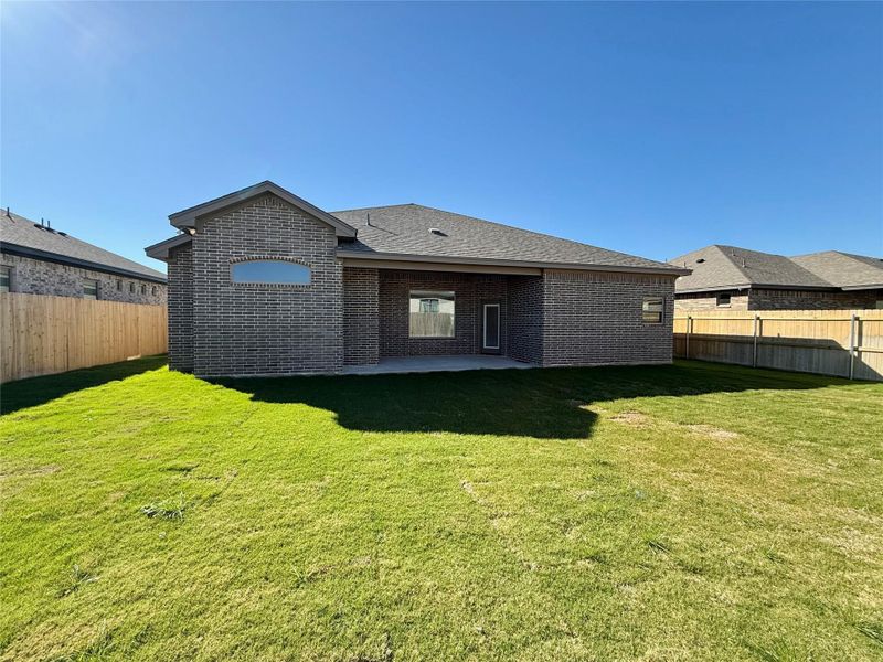 Back of house with a fenced backyard, brick siding, a patio, and a shingled roof