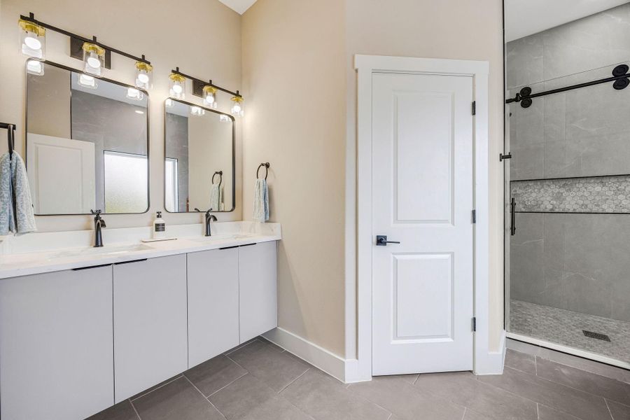Spa-inspired primary bath with dual vanities, oversized walk-in shower, and modern finishes. Spa-inspired primary bath with dual vanities, oversized walk-in shower, and modern finishes.