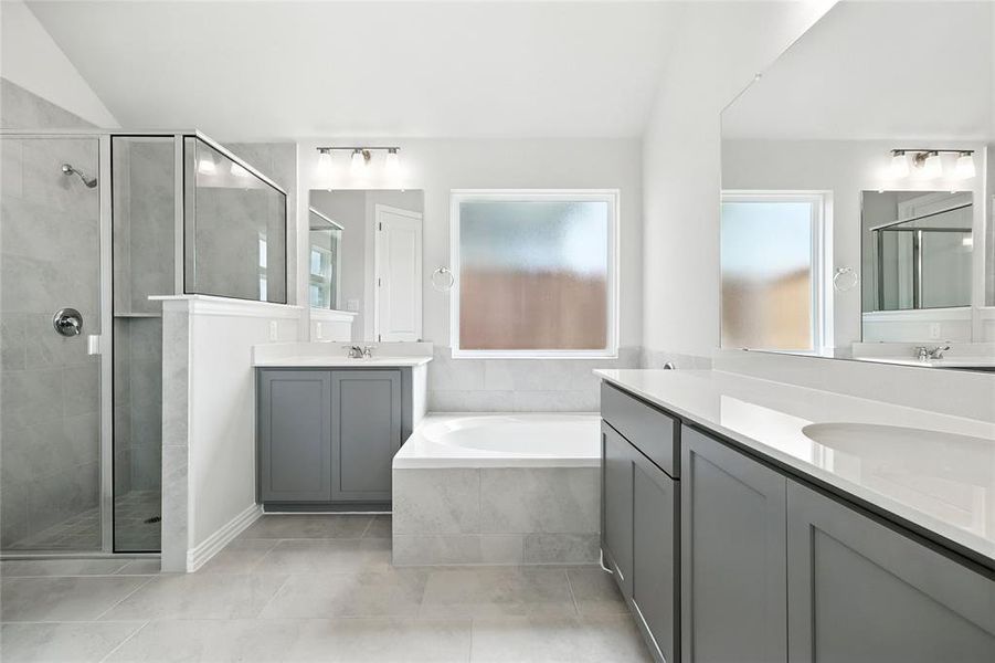 Full bath featuring a shower stall, two vanities, a garden tub, and light tile patterned flooring