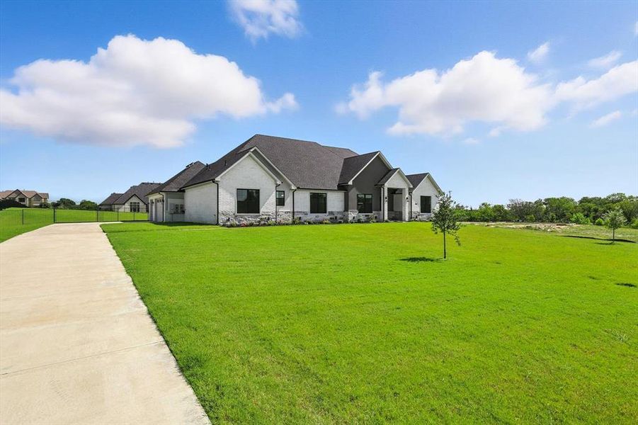 Modern farmhouse with stone siding, a front lawn, and roof with shingles Modern farmhouse with stone siding, a front lawn, and roof with shingles