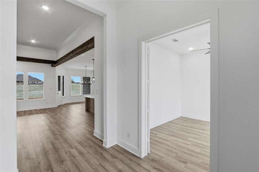 Hallway with light wood-style flooring, crown molding, and a chandelier