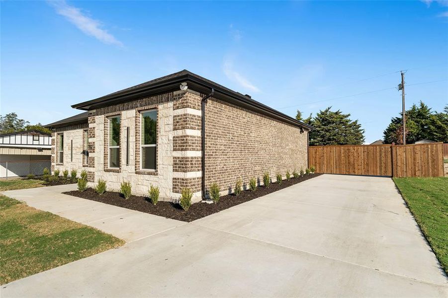 View of home's exterior with brick siding, stone siding, and concrete driveway