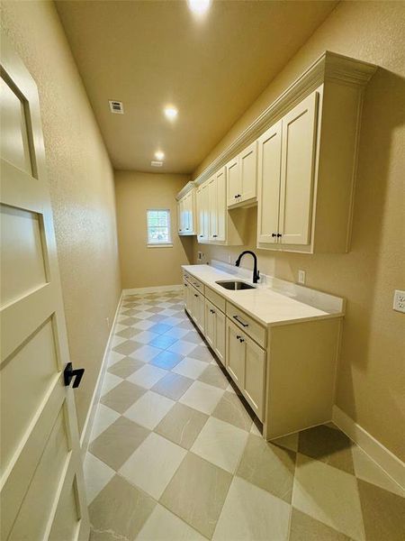 Kitchen with light floors, a textured wall, light stone counters, and recessed lighting Kitchen with light floors, a textured wall, light stone counters, and recessed lighting