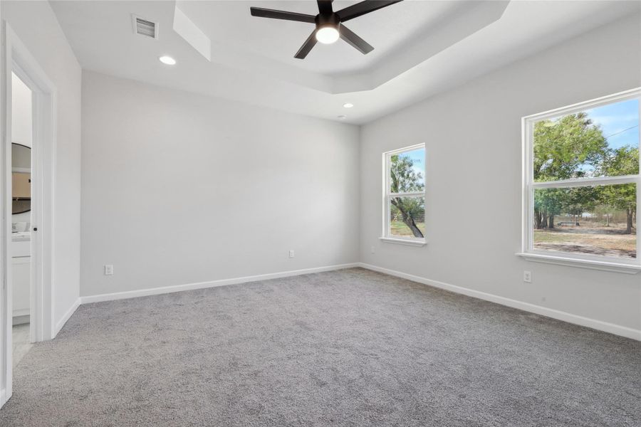 Spare room with ceiling fan, carpet flooring, a tray ceiling, recessed lighting, and baseboards Spare room with ceiling fan, carpet flooring, a tray ceiling, recessed lighting, and baseboards