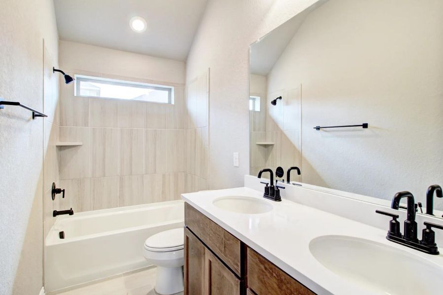 Full bath with double vanity, shower / bath combination, and a textured wall Full bath with double vanity, shower / bath combination, and a textured wall