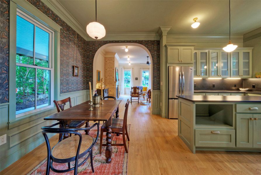 An inviting open-concept kitchen and dining area features stylish wallpaper, gorgeous moldings  and seamless flow into adjacent living spaces.