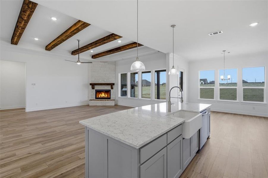 Kitchen with a fireplace, gray cabinetry, pendant lighting, light wood-style floors, and beam ceiling