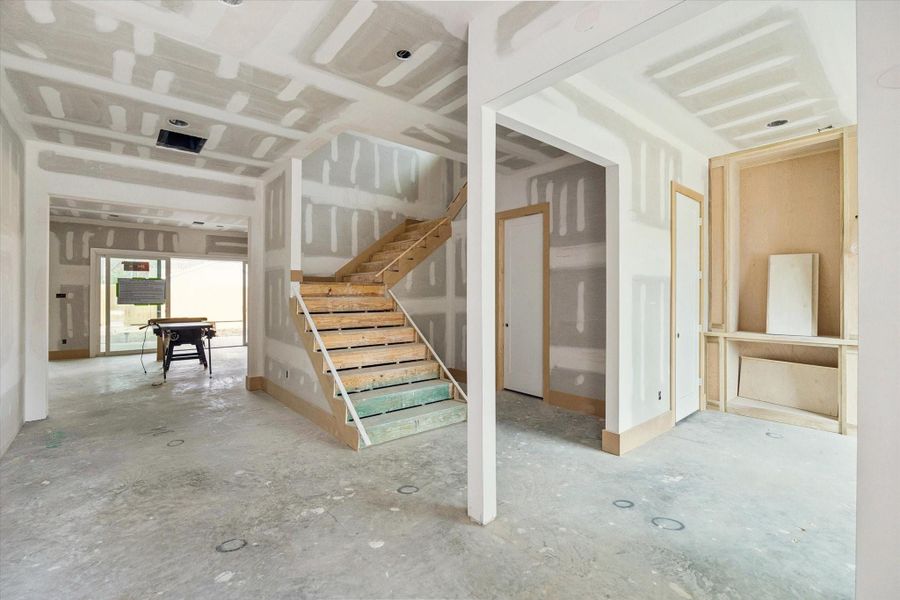 Expansive open layout anchored by a central staircase and framed sightlines from front to back. Ten foot ceilings, wide trim details, and recessed lighting set the stage for seamless flow into the living area and covered patio beyond.