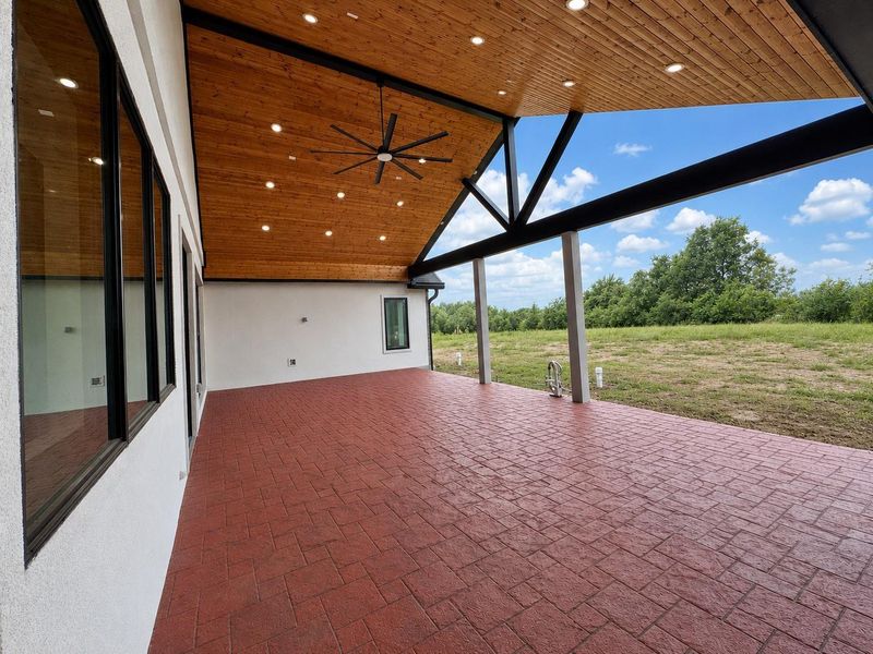 Expansive 40x20 covered outdoor living pavilion designed for year-round enjoyment. Two access points from house. Wood ceiling, oversized ceiling fan, recessed LED lighting, stamped concrete. Space offers ample room for multiple seating and dining areas and is already plumbed for a future outdoor kitchen. Also features a full outdoor bathroom for added convenience. This inviting outdoor retreat is the perfect extension of the home's living space for entertaining, relaxing, or enjoying quiet Texas evenings