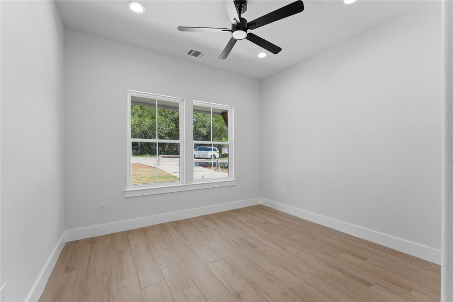 Secondary Bedroom #1 looking in from the door. Both downstairs bedrooms feature large windows overlooking the quiet backyard and natural greenspace beyond. The are situated on opposite sides of the home with a large secondary bathroom in a hallway between them.
