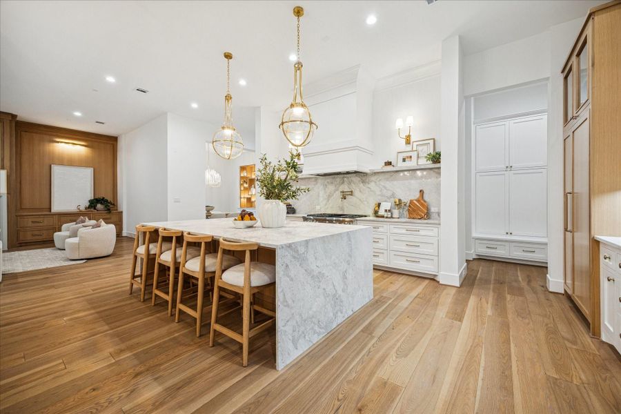 Statement pendants illuminate the generous island workspace. Wide-plank oak floors, high ceilings, and spray foam insulation create an efficient, acoustically balanced environment connected to the living and dining spaces. The first floor's 12 ft ceilings elevate the space.