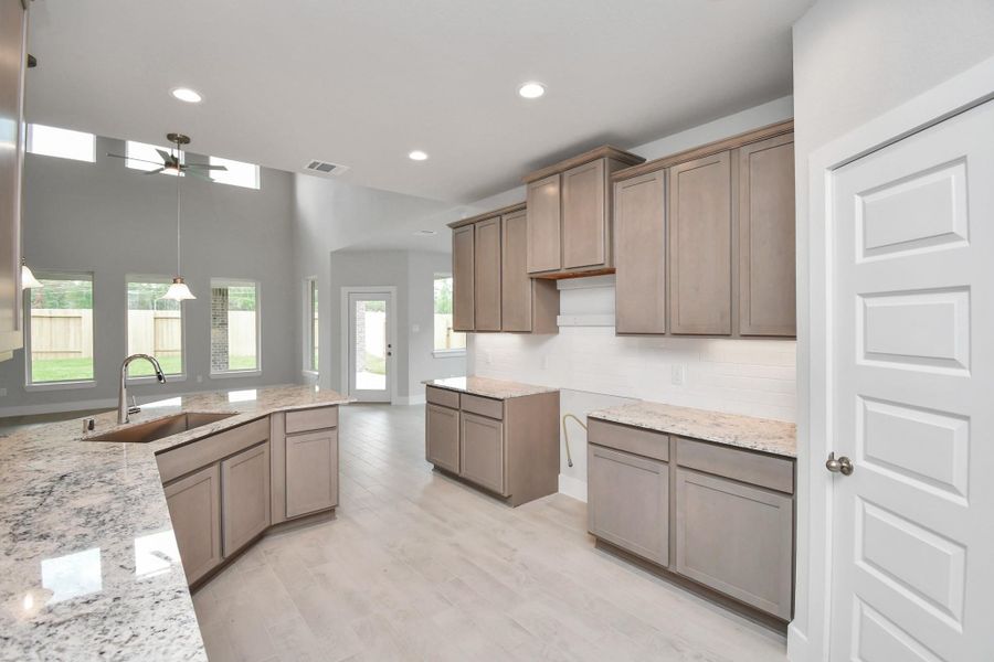 This kitchen is by far any chef’s dream! This spacious kitchen features high ceilings, stained wood cabinets, granite countertop, SS appliances, modern tile backsplash, recessed lighting, and an extended counter space. Sample photo of completed home with similar floor plan. Actual colors and selections may vary. This kitchen is by far any chef’s dream! This spacious kitchen features high ceilings, stained wood cabinets, granite countertop, SS appliances, modern tile backsplash, recessed lighting, and an extended counter space. Sample photo of completed home with similar floor plan. Actual colors and selections may vary.