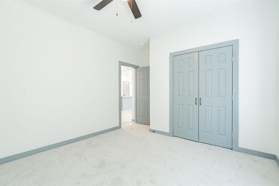 Unfurnished bedroom featuring carpet floors, ceiling fan, and a closet