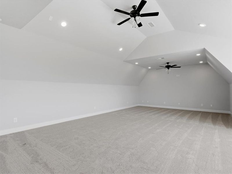 Spacious bonus room featuring vaulted ceilings, recessed lighting, two ceiling fans with integrated lighting, light gray carpeting, and painted white trim