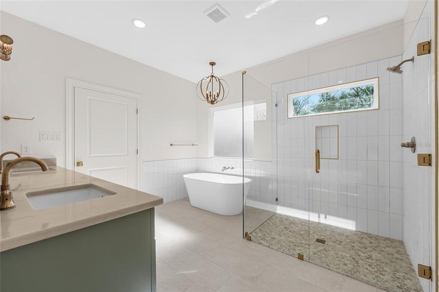 Bathroom featuring a freestanding bath, a stall shower, double vanity, tile walls, and a chandelier Bathroom featuring a freestanding bath, a stall shower, double vanity, tile walls, and a chandelier