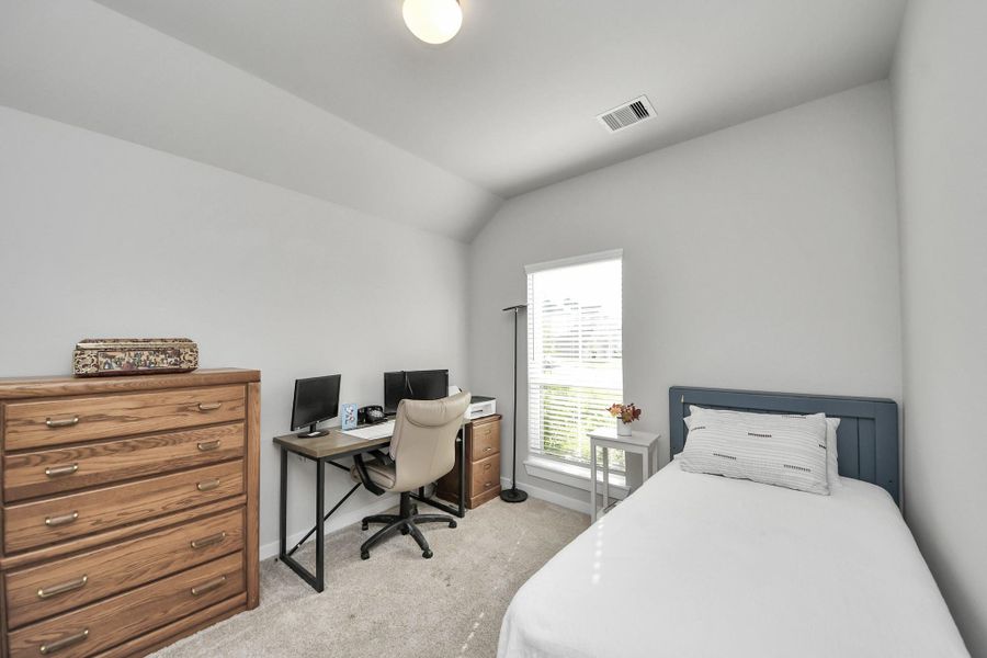 A gentle ceiling slope lends a cozy alcove feel, complemented by soft carpeting and enough room for a dedicated study desk.