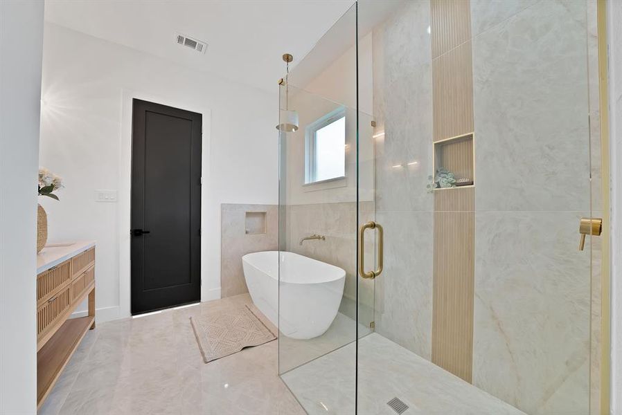 The bathroom features a freestanding bathtub, a glass-enclosed shower, and a modern vanity with a white countertop