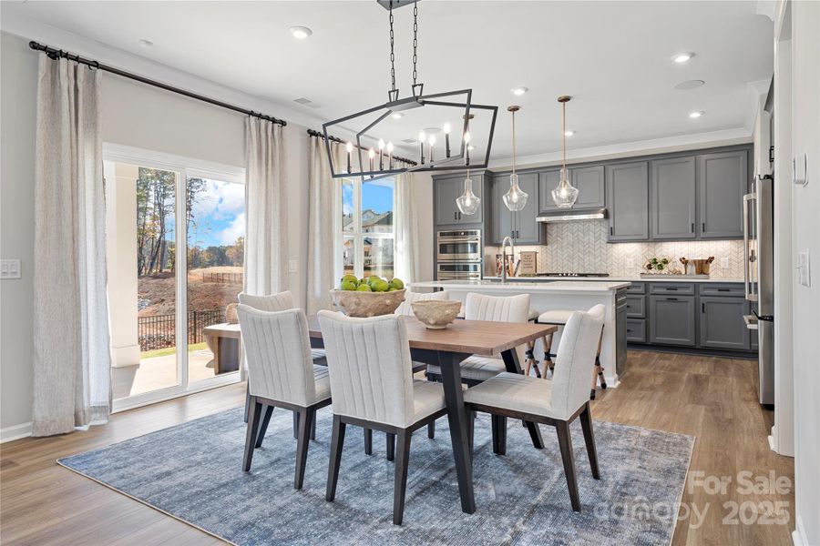 Dining space connected to kitchen with designer lighting.