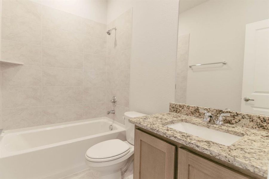 Full bathroom featuring vanity, tiled shower / bath combo, and toilet