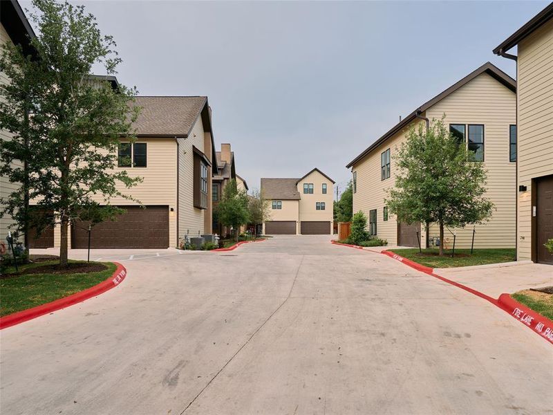 Townhome-style residences featuring light-colored siding, dark trim, and attached garages