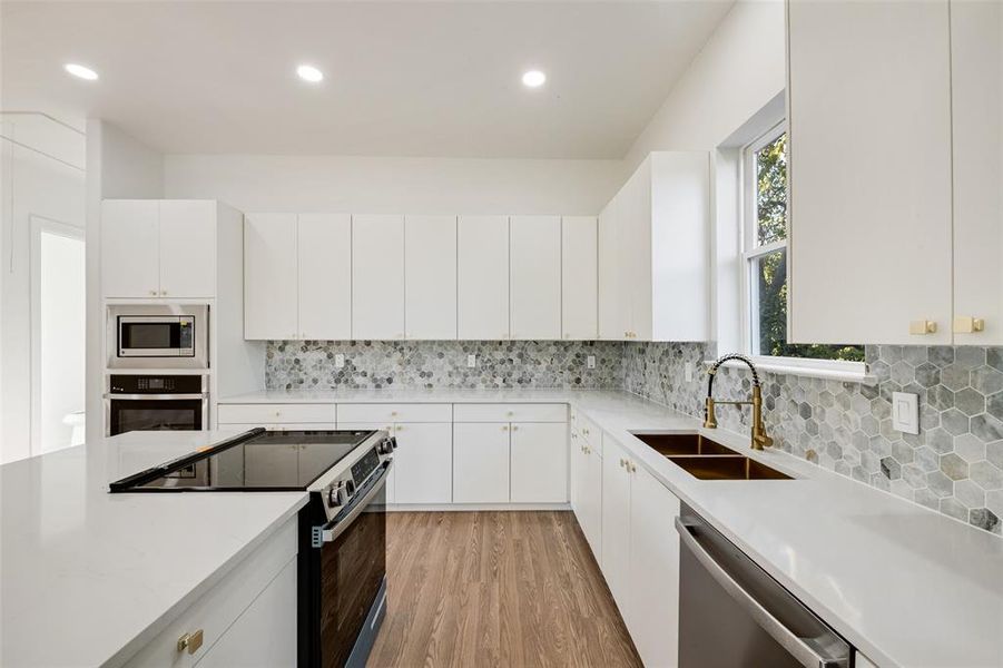 Kitchen with stainless steel appliances, light wood finished floors, white cabinets, tasteful backsplash, and recessed lighting Kitchen with stainless steel appliances, light wood finished floors, white cabinets, tasteful backsplash, and recessed lighting