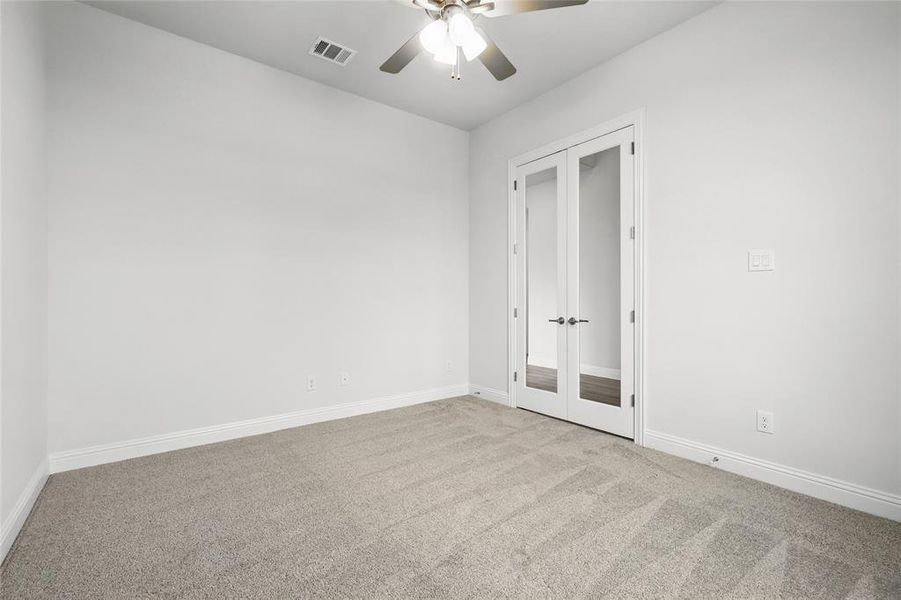 Unfurnished bedroom with visible vents, baseboards, ceiling fan, french doors, and carpet flooring Unfurnished bedroom with visible vents, baseboards, ceiling fan, french doors, and carpet flooring