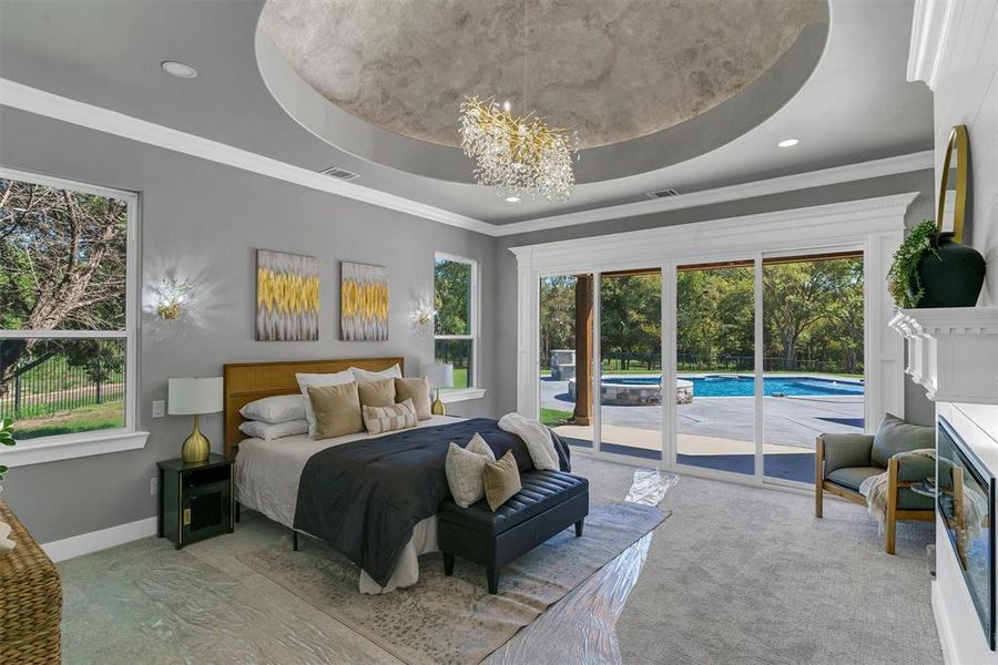 Bedroom with a raised ceiling, a notable chandelier, light carpet, access to outside, and crown molding