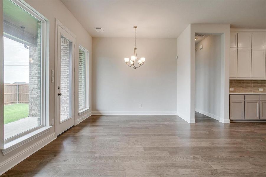 Unfurnished dining area featuring light hardwood / wood-style flooring, a chandelier, and a healthy amount of sunlight