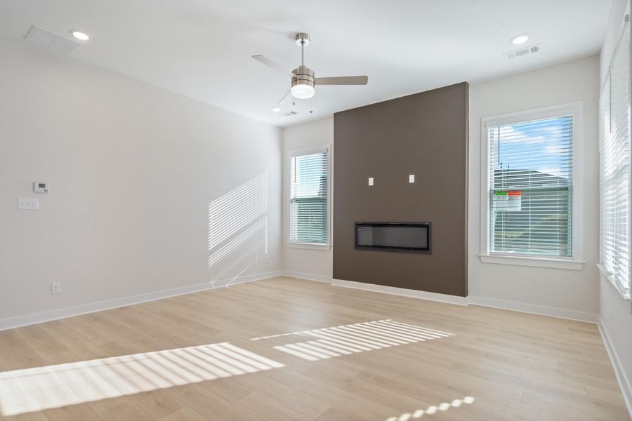 Open-concept living space featuring wood-finish flooring, recessed lighting, and a modern linear fireplace