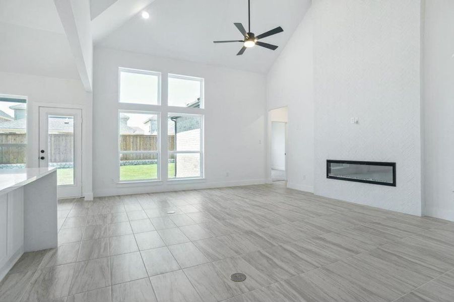 Unfurnished living room featuring beamed ceiling, ceiling fan, high vaulted ceiling, and a wealth of natural light