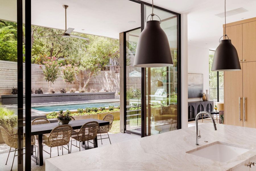 Kitchen featuring light stone countertops, light brown cabinetry, a wall of windows, and modern cabinets Kitchen featuring light stone countertops, light brown cabinetry, a wall of windows, and modern cabinets