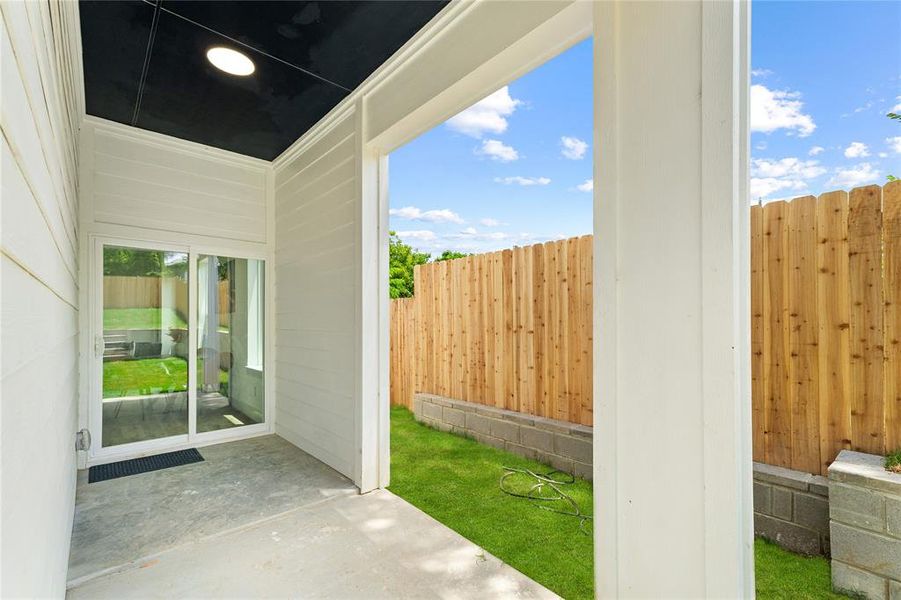 Covered patio featuring a concrete slab, white siding, and a black ceiling with recessed lighting