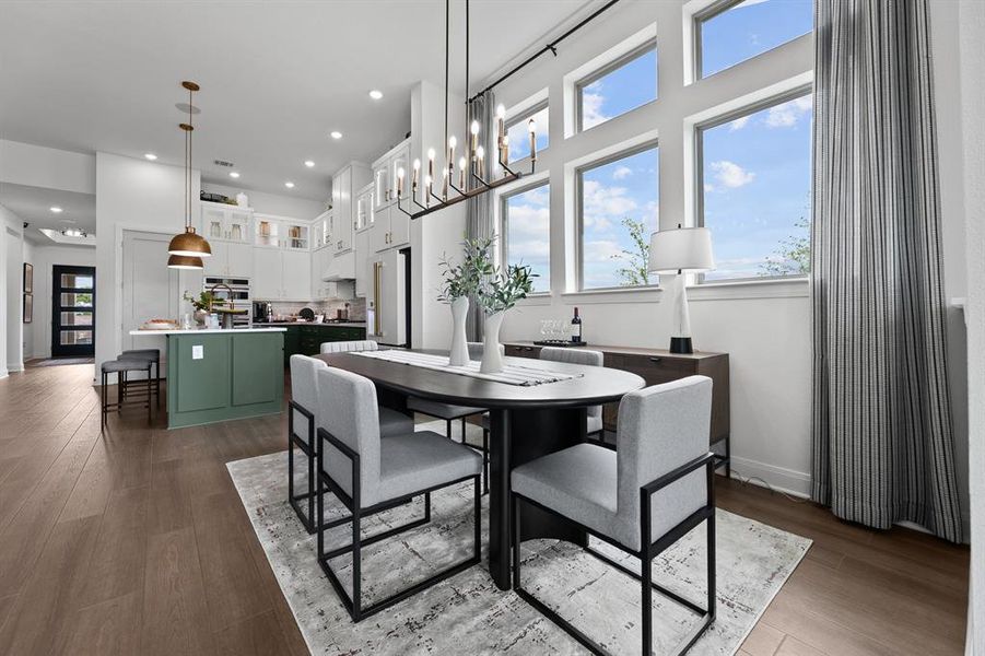 Dining space with dark wood-type flooring, a high ceiling, and hanging lights Dining space with dark wood-type flooring, a high ceiling, and hanging lights