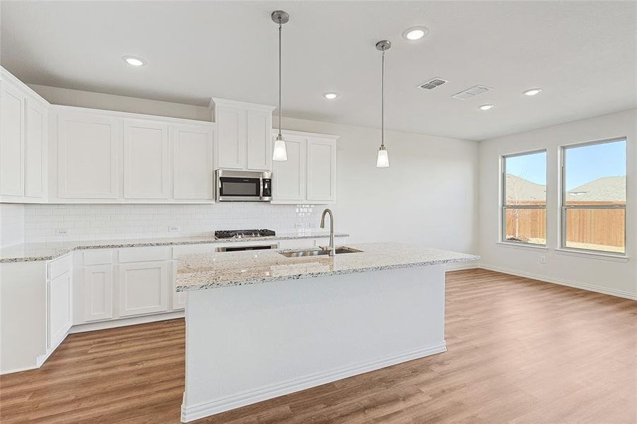 Kitchen featuring white cabinetry, light stone counters, and light wood-type flooring
