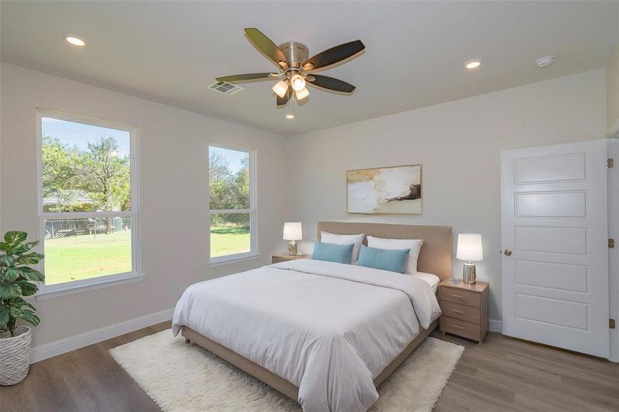 Bedroom with hardwood / wood-style floors, multiple windows, and ceiling fan