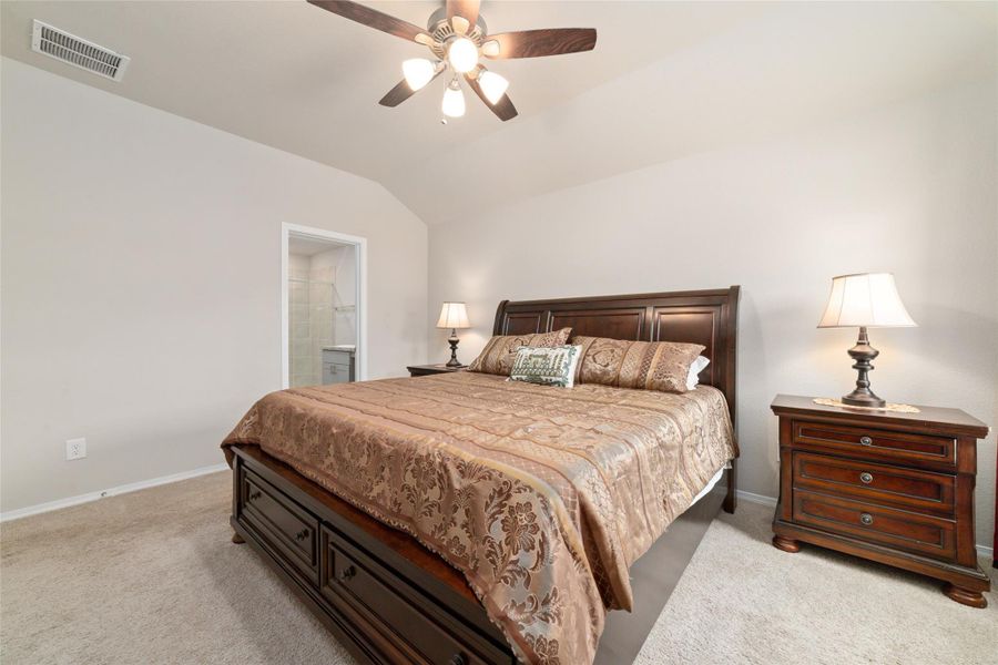 Spacious primary bedroom with high ceilings and a ceiling fan, offering a bright and airy feel with easy access to the ensuite bath.