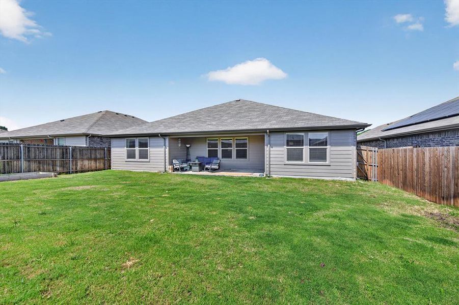 Expansive backyard featuring a large grass lawn, privacy fencing, and an extended covered patio