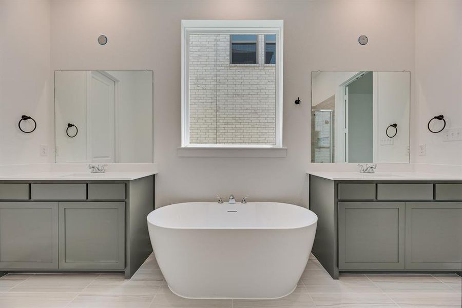 Full bathroom featuring two vanities, a freestanding bath, and light tile patterned floors Full bathroom featuring two vanities, a freestanding bath, and light tile patterned floors