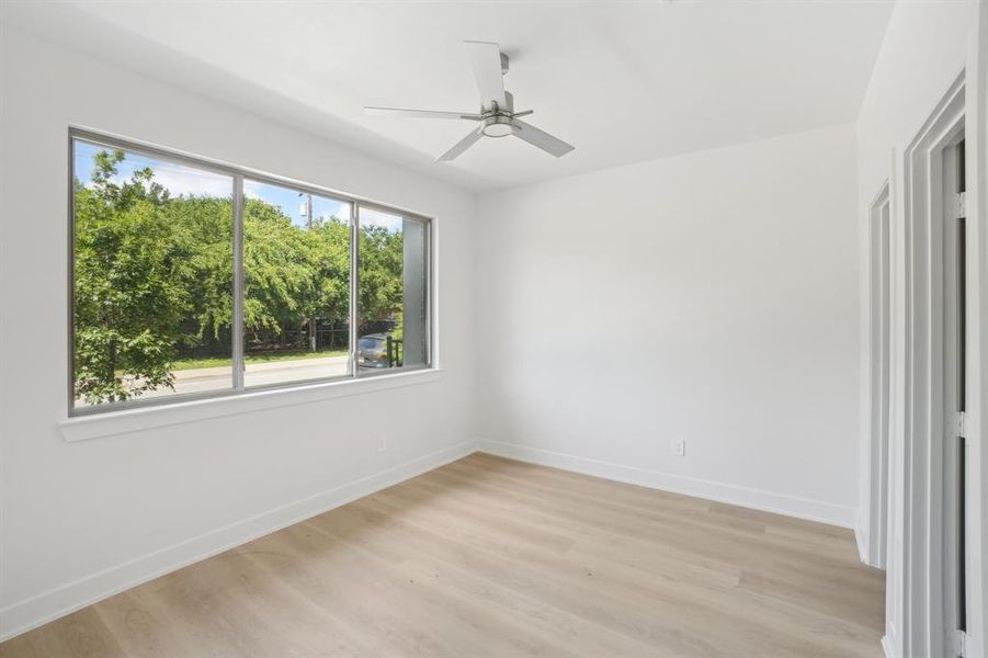 Empty room featuring light wood finished floors, baseboards, and ceiling fan