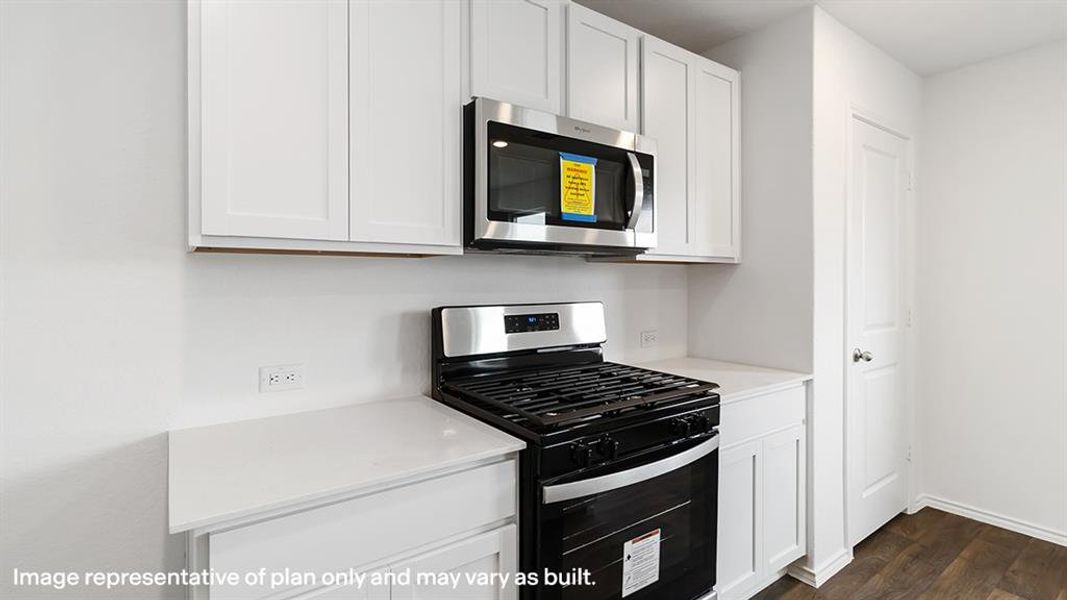 Kitchen with stainless steel appliances, white cabinets, dark wood-style floors, and light stone countertops