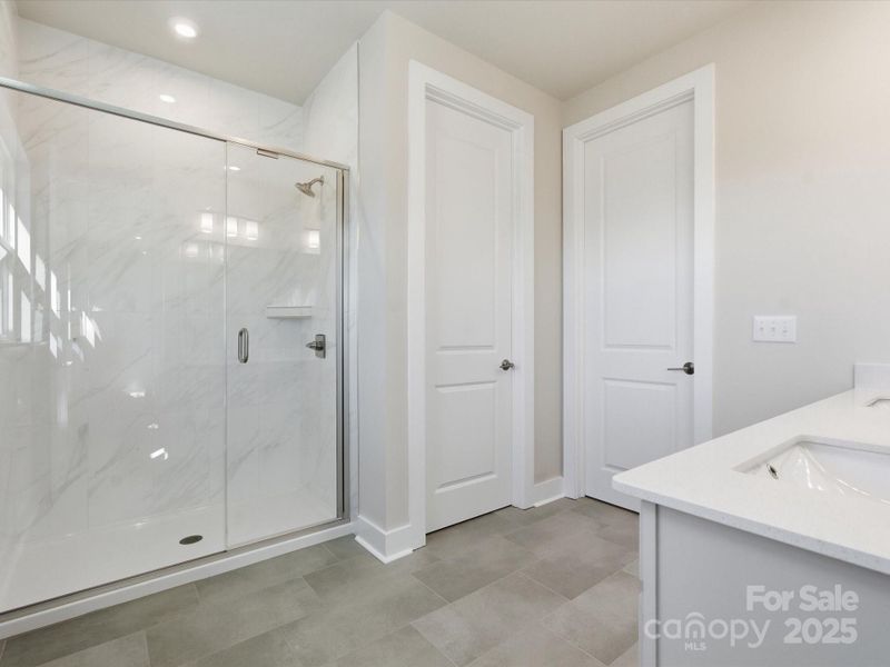 En Suite Primary Bath With Large Scale Marble-Look Tile.